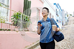 Happy young woman walking with cellphone and bag