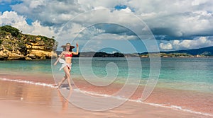 Happy young woman walking through shallow sea water on the beach