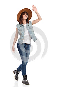 Happy Young Woman Is Walking, Waving Hand And Looking Away