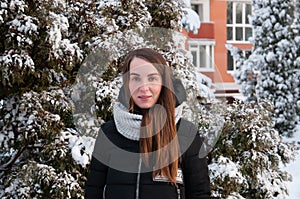 Woman in winter down jacket in winter park on background of snow-covered fir