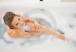 Happy young woman washing in bathtub