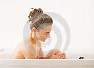 Happy young woman washing in bathtub