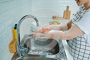 Happy Young Woman Washing Dishes in the kitchen