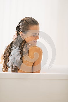 Happy young woman washing hair