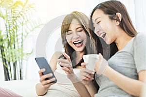 Happy young woman watching their smart phones  sitting on  sofa  at home