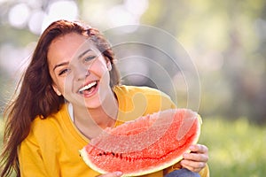 Happy young woman with watermelon in the park.