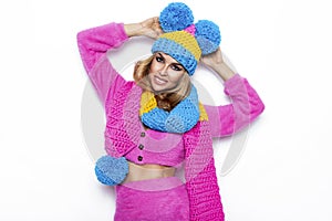 Happy young woman wearing a colorful knitted winter hat, sweater and scarf over white background. Winter fashion