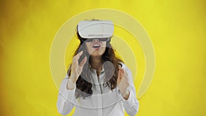 Happy young woman Wearing Virtual Reality Headset on yellow background at studio