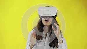 Happy young woman Wearing Virtual Reality Headset on yellow background at studio