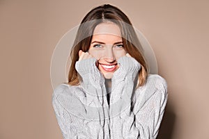 Happy young woman wearing warm sweater on background