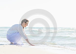 Happy young woman wetting hands in sea photo