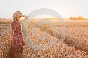Happy young woman in wheat field by sunset, daydream