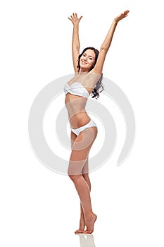 Happy young woman in white bikini swimsuit dancing