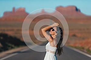 Happy young woman in white dress on the famous road to Monument Valley in Utah. Amazing view of the Monument valley.