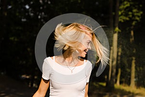 Happy young woman in white t shirt with hair in wind posing on