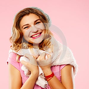 Happy young woman in winter sweather with knitted headphones over pink background