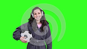 Happy young woman in wireless headphones catching the ball on the chroma key