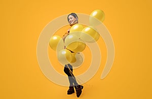 Happy young woman with yellow balloons in studio