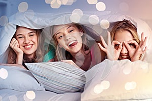 Happy young women in bed at home pajama party