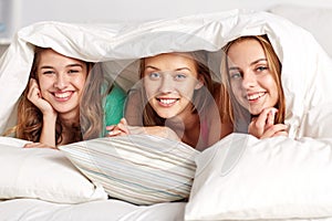 Happy young women in bed at home pajama party