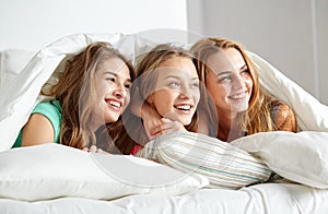 Happy young women in bed at home pajama party