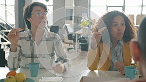 Happy young women Caucaisan and Afro-American talking laughing eating pizza in office