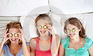 Happy young women with cucumber mask lying in bed