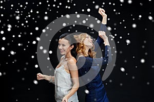 Happy young women dancing over snow