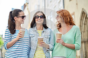 Happy young women drinking coffee on city street