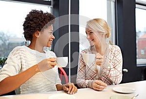 Happy young women drinking tea or coffee at cafe