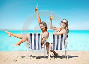 Happy young women with drinks sunbathing on beach