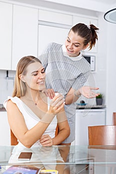 Happy young women looking betrothal ring and chatting together