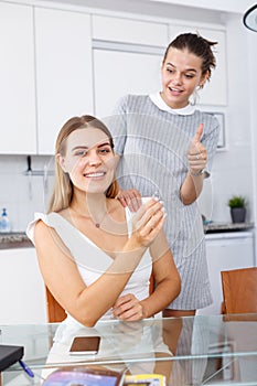 Happy young women looking betrothal ring and chatting together