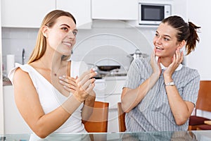 Happy young women looking betrothal ring and chatting together