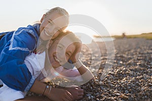 Happy young woman lying on her boyfriends back, looking at camera, having fun together.