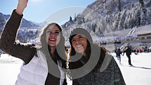 Happy young women making selfie by mobile phone, funny ice skating girls