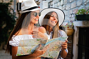 Happy young women with map in city. Travel tourist people fun concept.