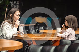 Happy young women mother with children sitting at dinner table and talking in restaurant