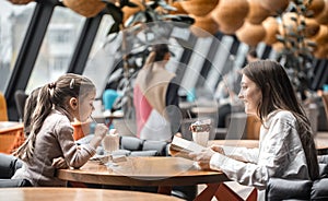 Happy young women mother with children sitting at dinner table and talking in restaurant