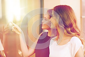 Happy young women pointing finger to shop window