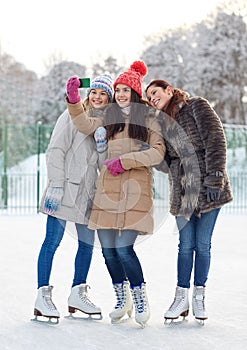 Happy young women with smartphone on skating rink