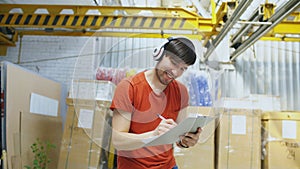 Happy young worker in industrial warehouse listening to music and dancing during work. Man in headphones have fun at