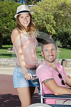 Happy youngman sitting on wheelchair with girlfriend