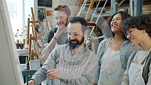 Happy youth milti-ethnic group talking to arts teacher and laughing during class in studio