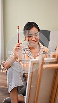 Happy young woman painting picture with watercolor at cozy home. Art, creative hobby and leisure activity concept