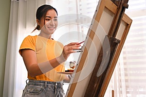 Happy young woman painting picture with watercolor at cozy home. Art, creative hobby and leisure activity concept