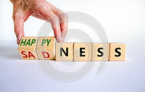 Happyness or sadness symbol. Businessman turns cubes and changes the word `sadness` to `happyness`. Beautiful white background