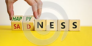 Happyness or sadness symbol. Businessman turns cubes and changes the word `sadness` to `happyness`. Beautiful white background