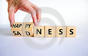 Happyness or sadness symbol. Businessman turns cubes and changes the word `sadness` to `happyness`. Beautiful white background
