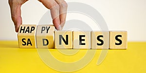 Happyness or sadness symbol. Businessman turns cubes and changes the word `sadness` to `happyness`. Beautiful white background